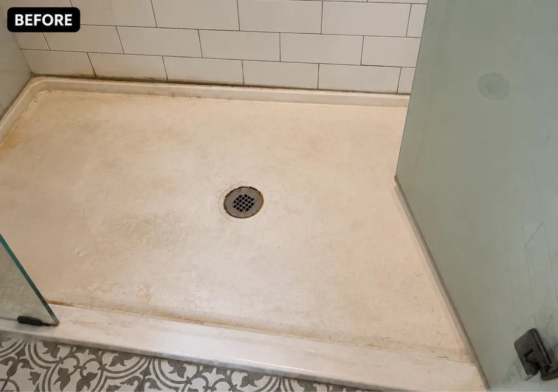 Shower floor before cleaning, showing grime and stains around drain area.