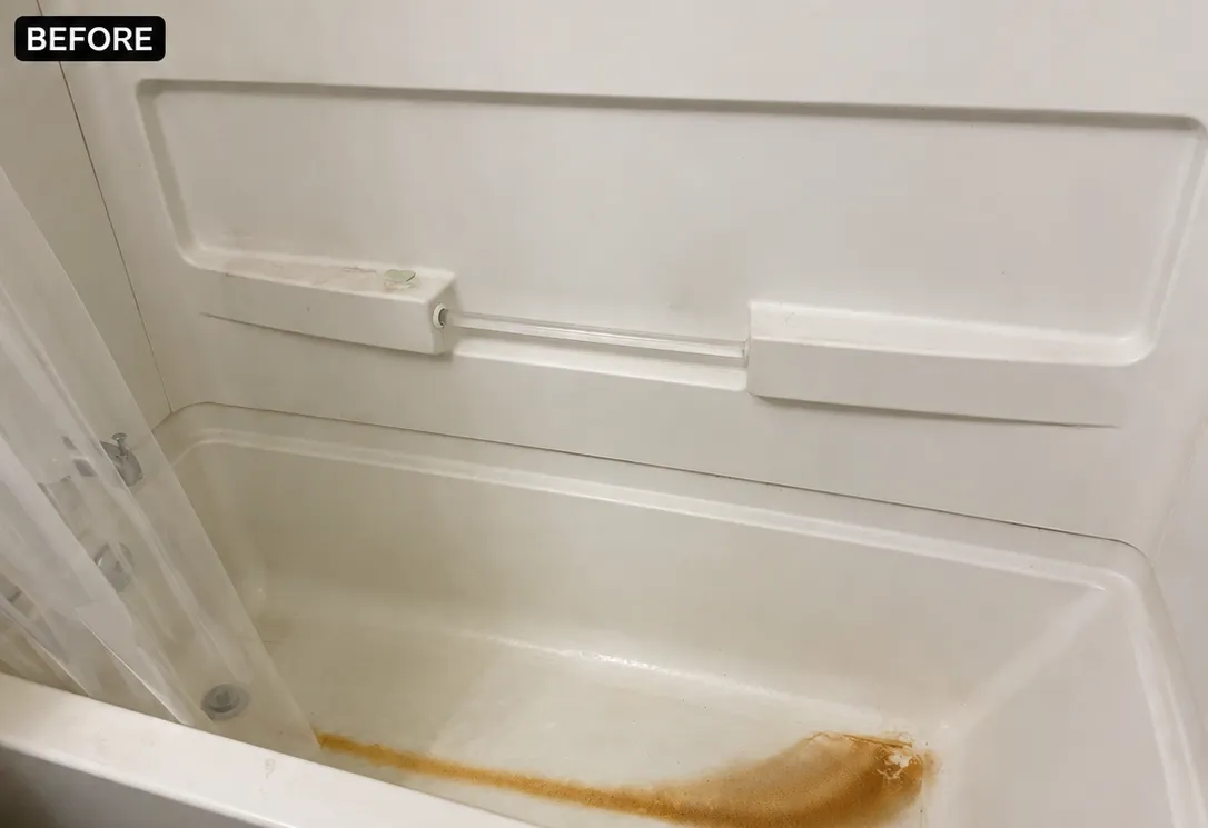 Dirty bathtub before cleaning, showing rust stains and soap buildup.
