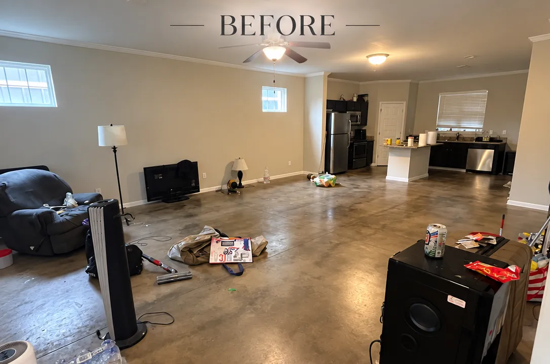 Cluttered living room before renovation, featuring furniture, appliances, and scattered items.