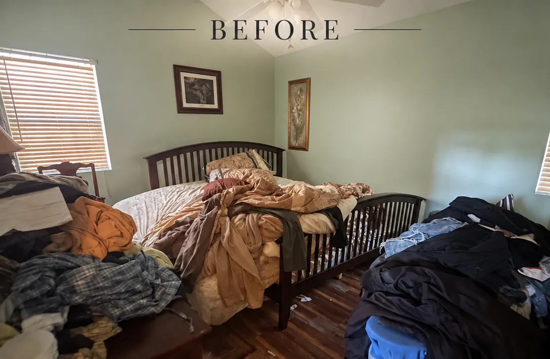 Cluttered bedroom with unmade bed and piles of clothes before organization.