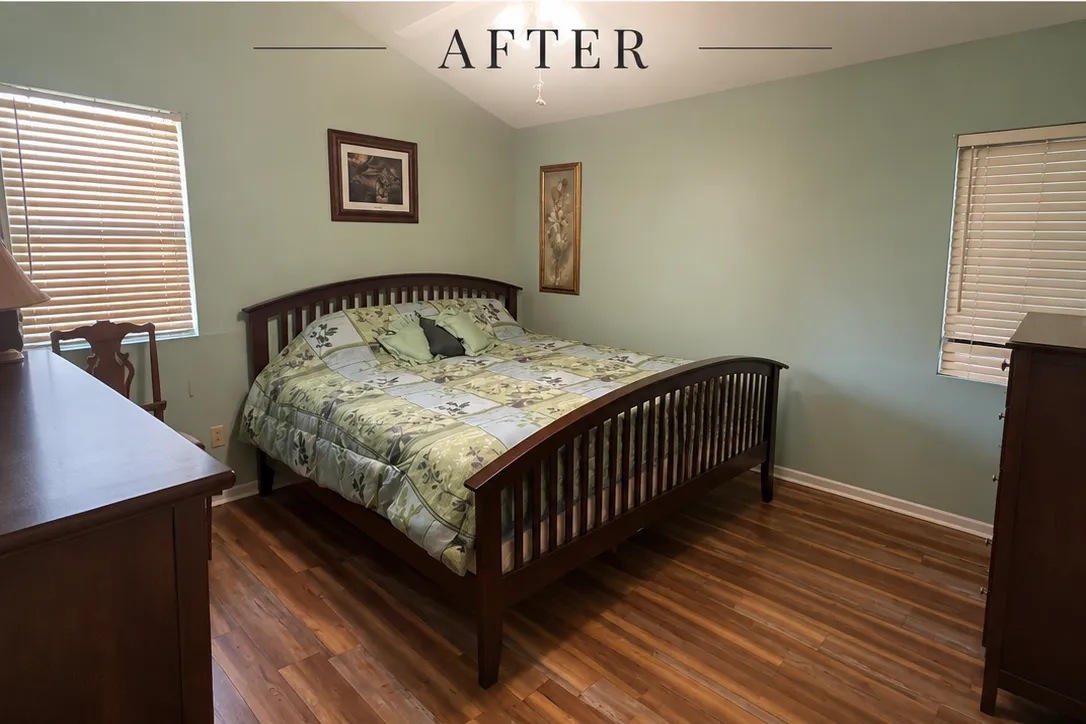 Cozy bedroom with a wooden bed, green walls, and natural light from window blinds.
